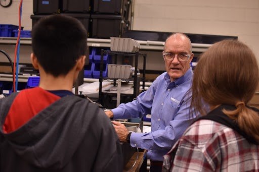 Nick Hackett, President of New Way Air Bearings, shows students from the “What’s So Cool About Manufacturing?” competition the intricacies of one of the manufacturing machines at New Way Air Bearings. 