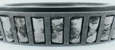 Close up image of a roller bearing with heavy spalling damage on the individual roller surfaces