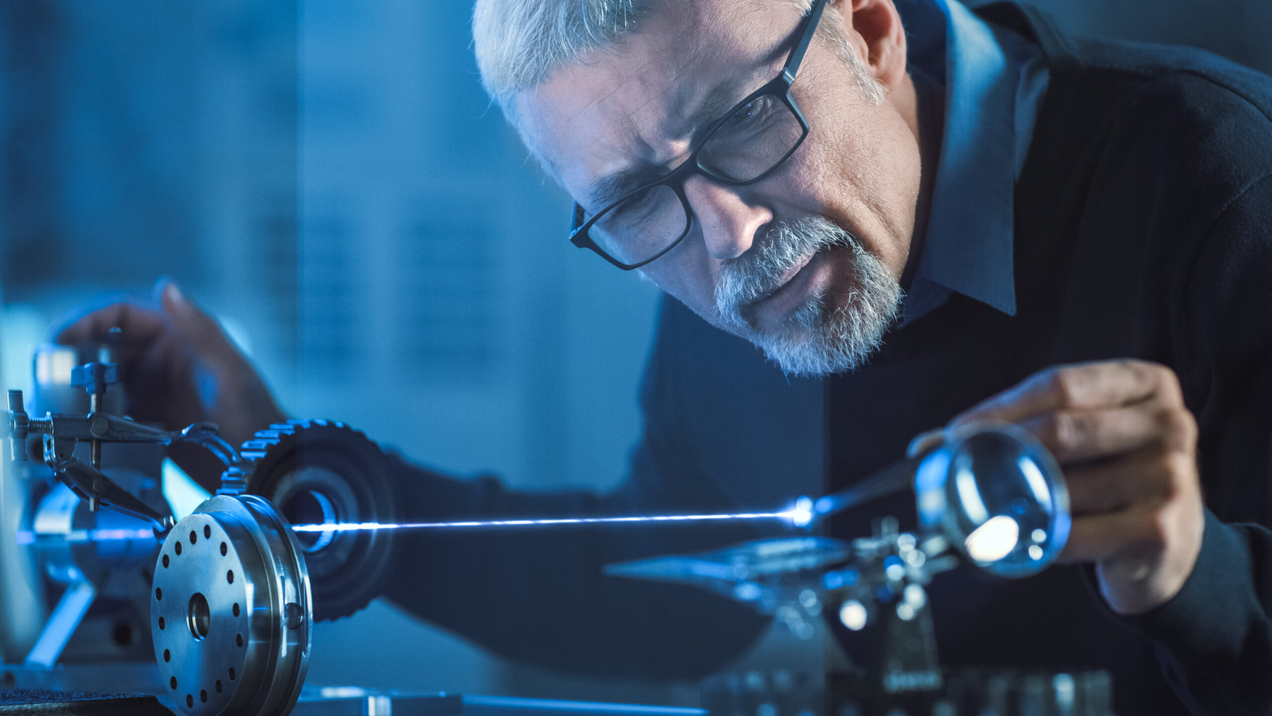 A man stands over a visible laser beam in a laboratory setting